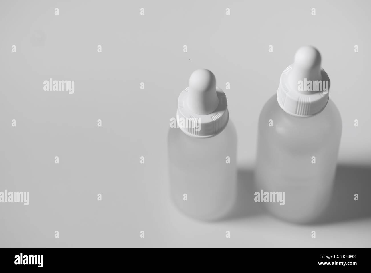 Vue de dessus de deux flacons compte-gouttes en verre translucide vides. Flacons de différentes tailles sur fond blanc. Maquette horizontale et espace de copie. Banque D'Images