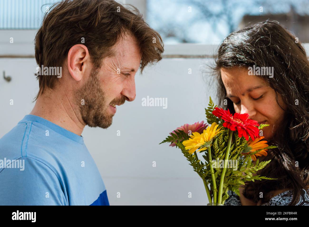 adulte latino caucasien d'origine argentine, à la maison il est nerveux donnant un bouquet de fleurs à sa femme enceinte. Banque D'Images