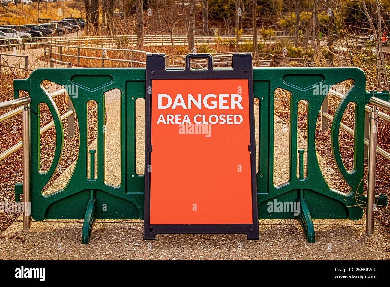 Portail modulaire vert extérieur sur galets publics et trottoir en béton avec affichage sandwich lecture DANGER zone fermée - Bois et parking à distance Banque D'Images