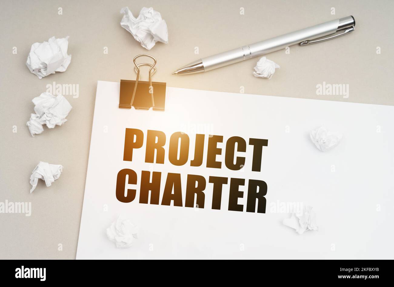 Concept économique et commercial. Sur une surface grise, un stylo, du papier froissé et une feuille avec l'inscription - Charte du projet Banque D'Images