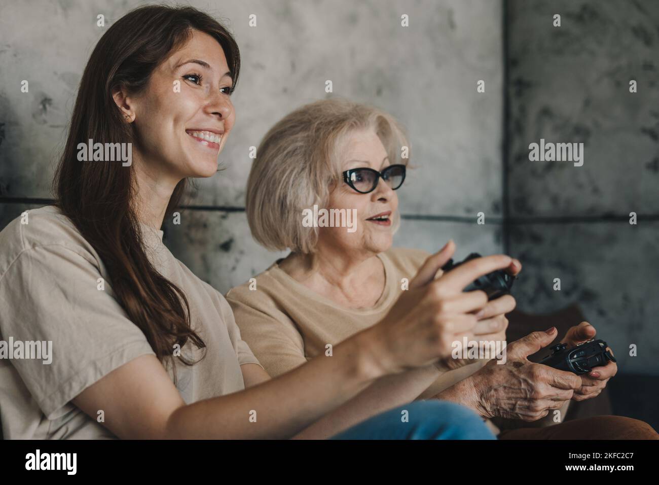 Deux générations de famille jouant à des jeux vidéo en utilisant des gamepads à la maison, aiment passer du temps ensemble. Un enfant souriant et heureux. Bonne famille. Vos amis jouent. Banque D'Images