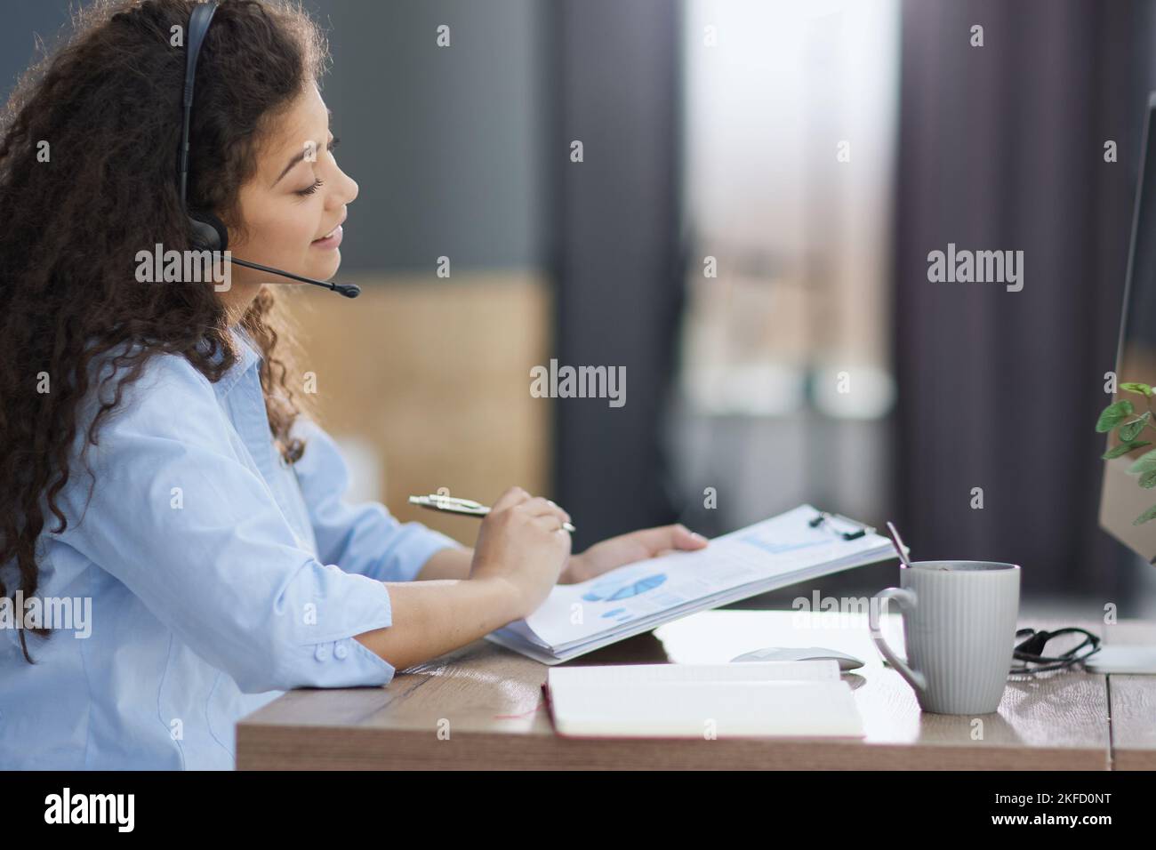 Vue latérale d'un opérateur joyeux dans un micro-casque/une oreillette au bureau Banque D'Images
