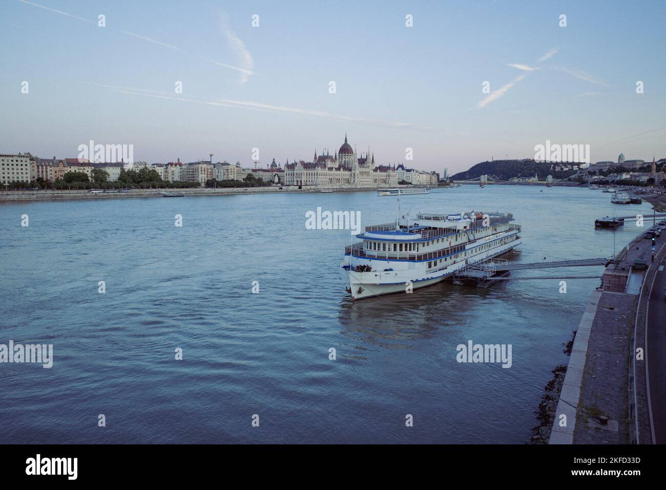 Le bâtiment du Parlement hongrois au bord du Danube dans la soirée derrière un gros navire dans le port Banque D'Images