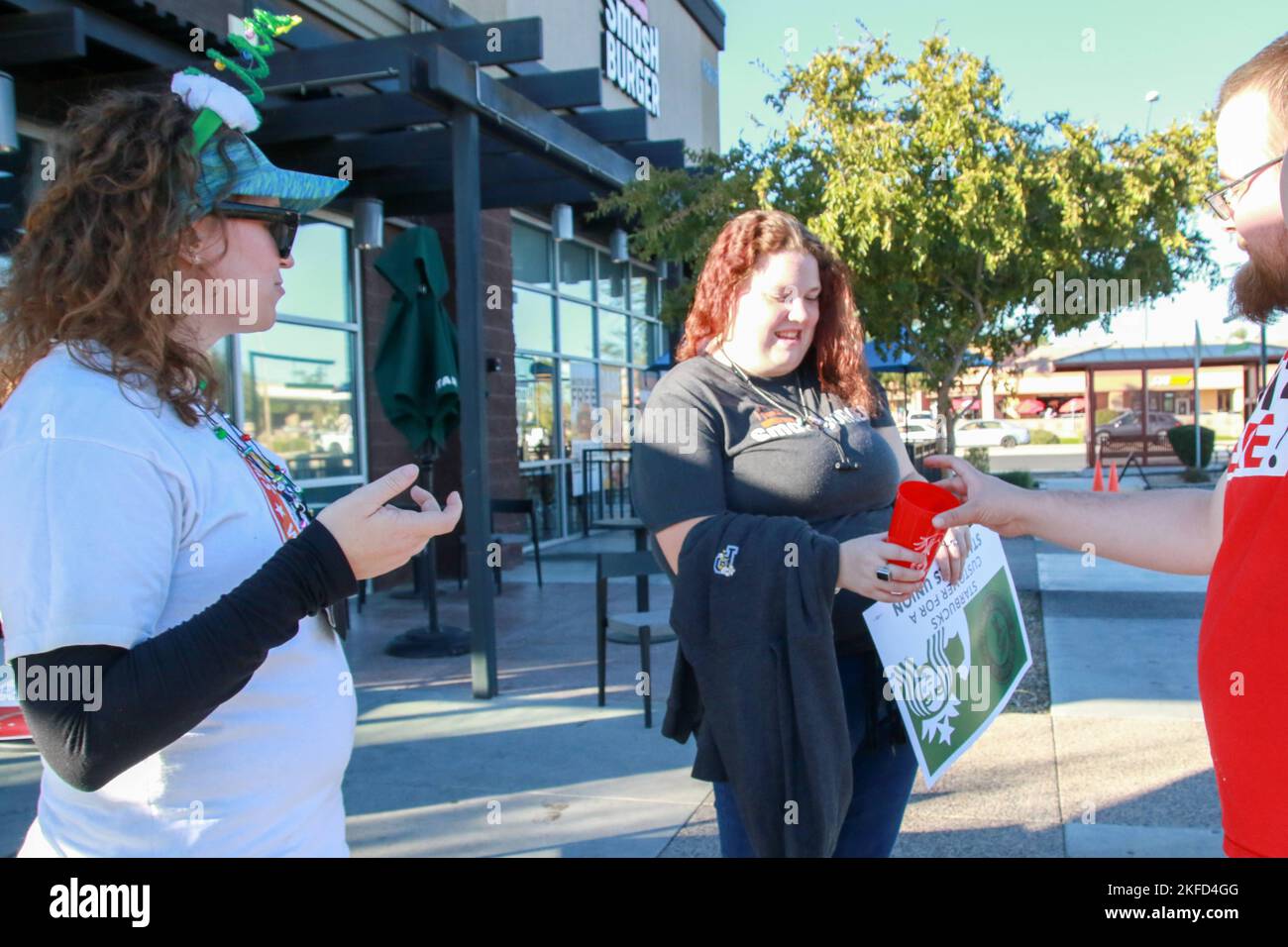Un client se voit remettre une coupe rouge « travailleurs Starbucks » qui montre le soutien syndical des travailleurs participant à la grève nationale d'une journée dans le premier magasin de l'Arizona à se syndiquer à Mesa, Arizona, États-Unis, sur 17 novembre 2022. Plus de 2 000 employés de 112 sites Starbucks sont en grève dans ce qu'ils appellent la rébellion de la coupe Rouge pour protester contre les représailles prises contre les partisans syndicaux dans tout le pays. Les grévistes distribuent des gobelets « Red Starbucks Workers United » aux clients dans le cadre de la plus grande journée d'action coordonnée organisée par les magasins Starbucks de l'histoire de campaignÕs. (Photo de: Alexandrr Banque D'Images