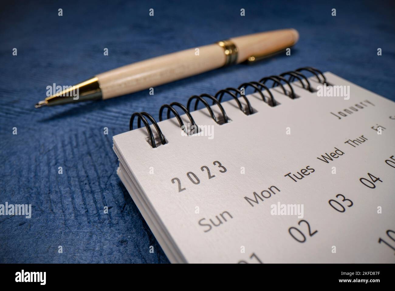 Janvier 2023 - calendrier de bureau en spirale contre papier bleu textures avec un stylo à bille, nouvel an, temps et concept d'affaires, macro prise de vue de la sonde de lentille pe Banque D'Images
