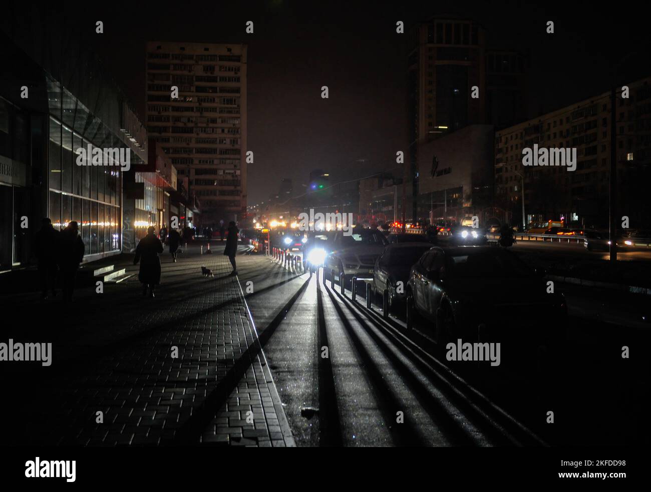 Kiev, Ukraine. 17th novembre 2022. La lumière des phares de voiture éclaire  les passants en marchant le long d'une rue sombre lors d'une coupure de  courant à Kiev. La Russie a envahi