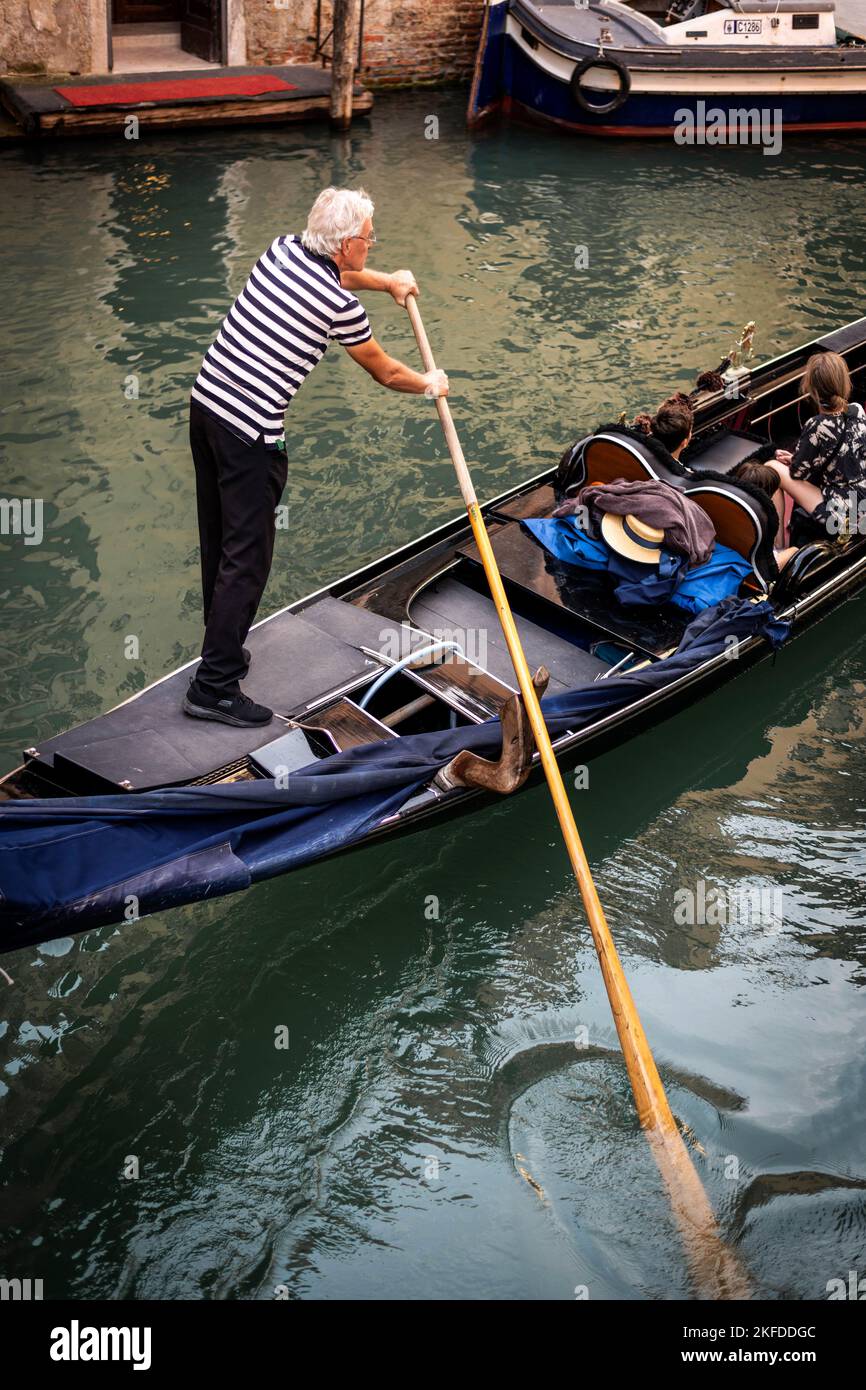 Gondolier à la tête d'une gondole, un bateau à rames vénitien traditionnel sur un canal à Venise, en Italie Banque D'Images