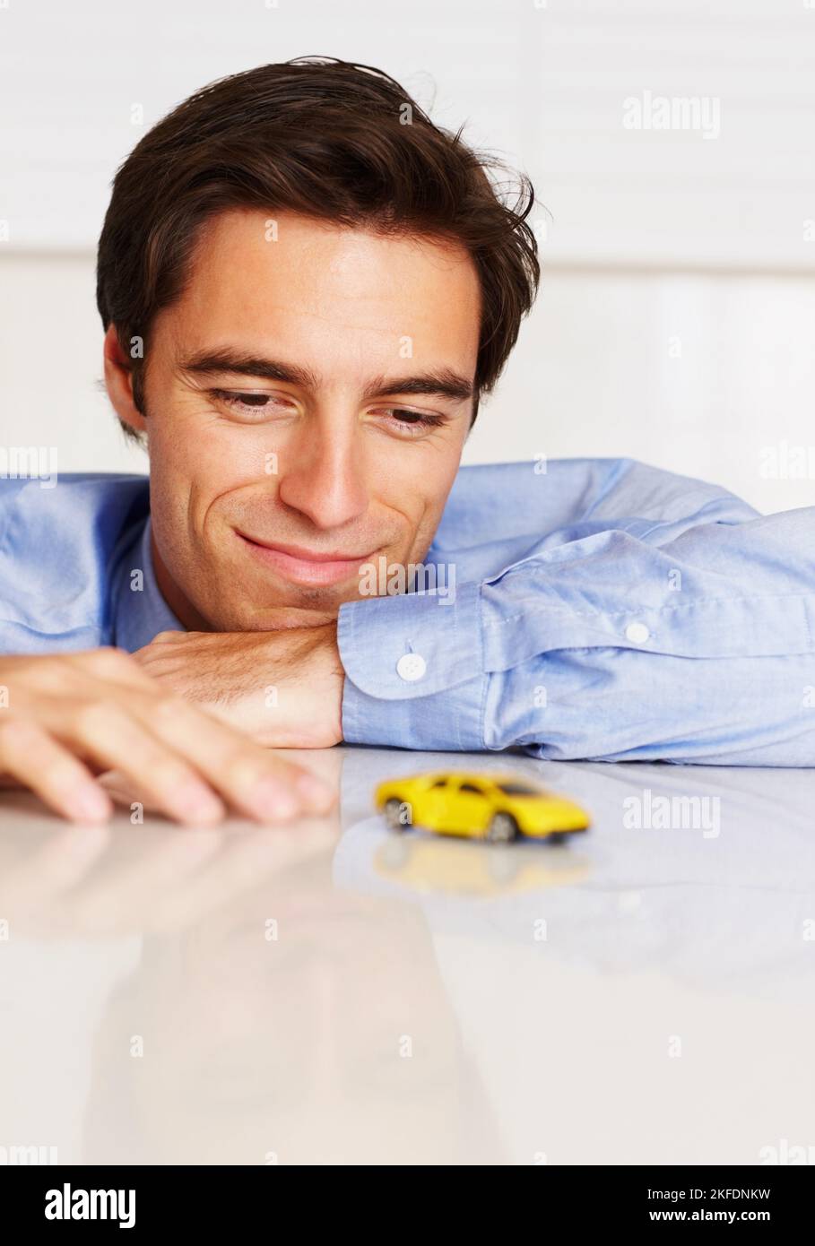 Homme jouant avec une voiture-jouet pensant à une nouvelle stratégie commerciale. Homme d'affaires jouant avec une voiture de jouet jaune pensant à la nouvelle stratégie d'affaires. Banque D'Images
