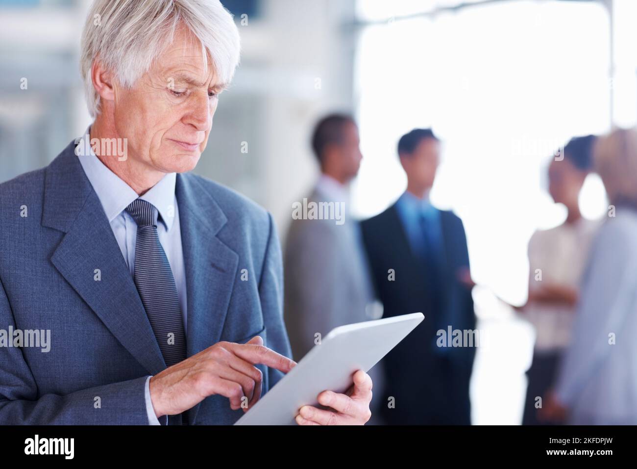 Cadre supérieur utilisant une tablette électronique. Portrait d'un cadre supérieur utilisant une tablette électronique avec des cadres en arrière-plan. Banque D'Images