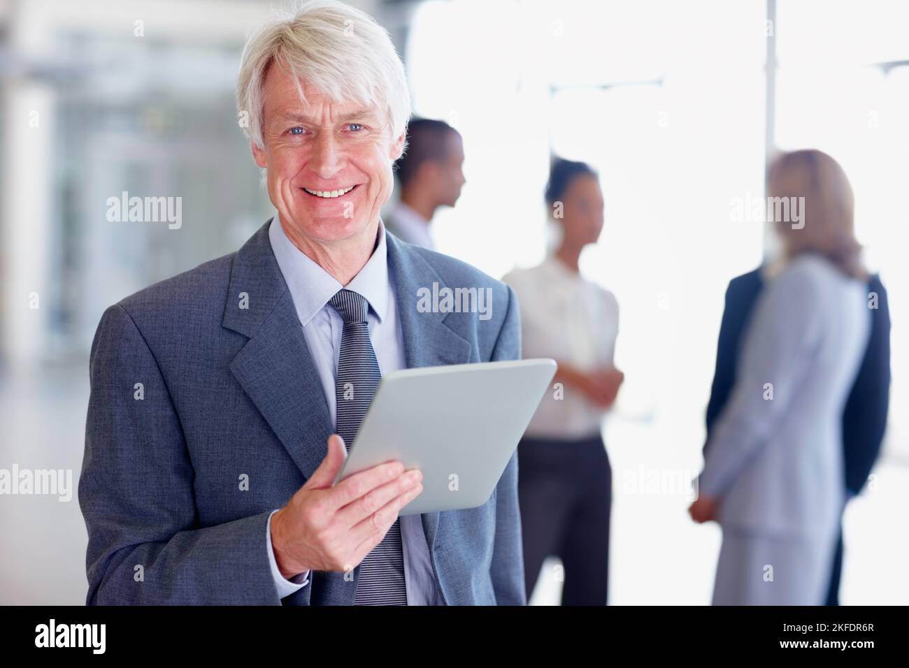 Beau homme d'affaires avec tablette électronique. Portrait d'un homme d'affaires chevronné souriant tout en utilisant une tablette numérique avec des cadres. Banque D'Images
