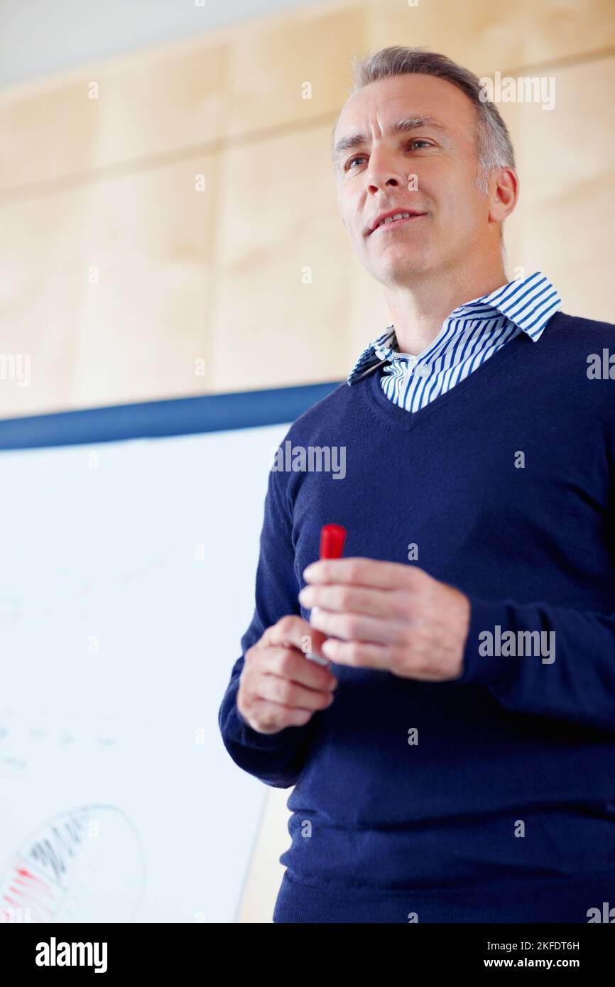 Cadre supérieur donnant la présentation. Homme senior debout à côté de la planche à dessin. Banque D'Images