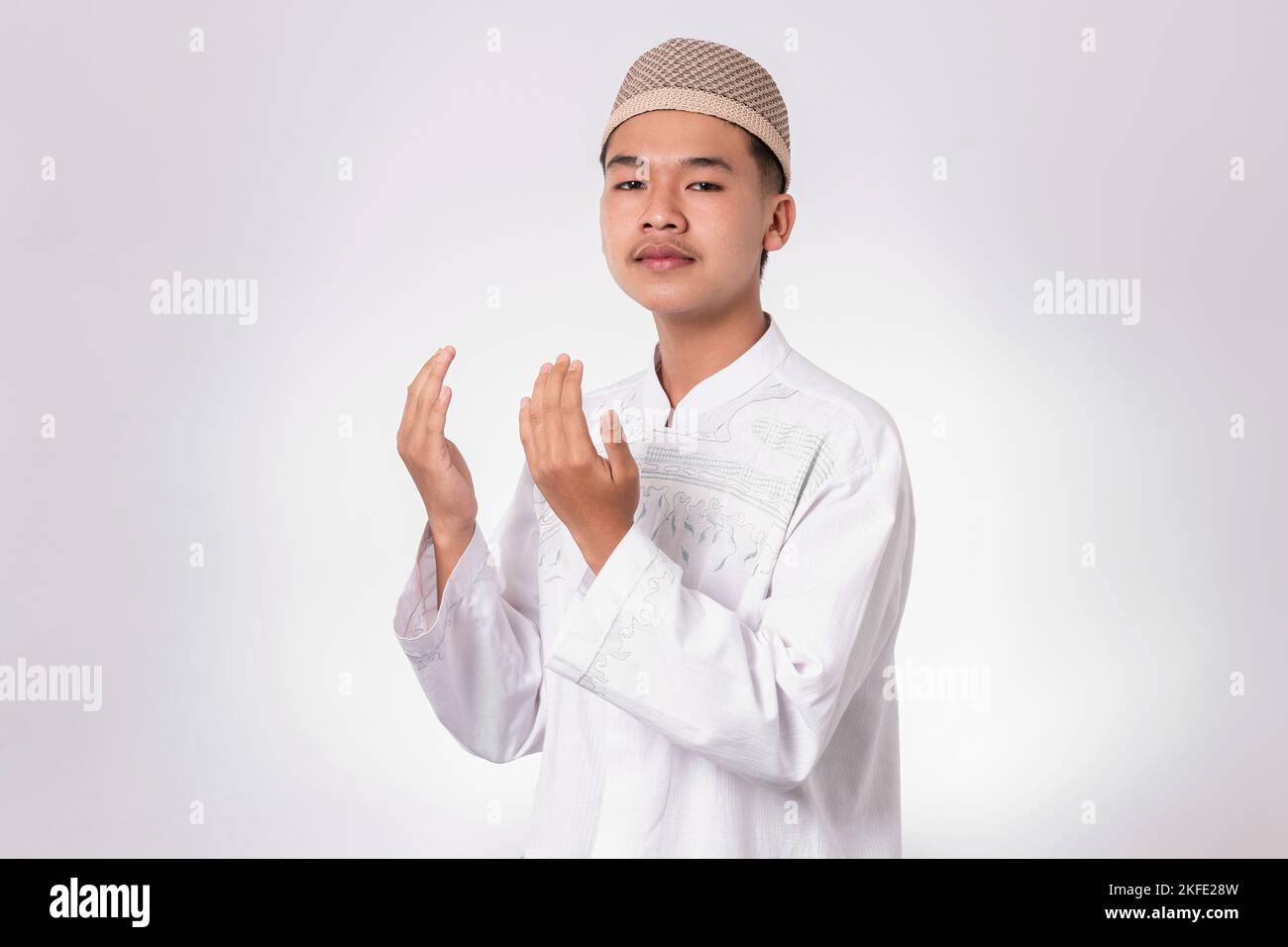 Souriant homme musulman asiatique heureux de célébrer Eid Al-Fitr isolé fond blanc. Célébrez le mois Saint du Ramadan dans l'Islam Banque D'Images