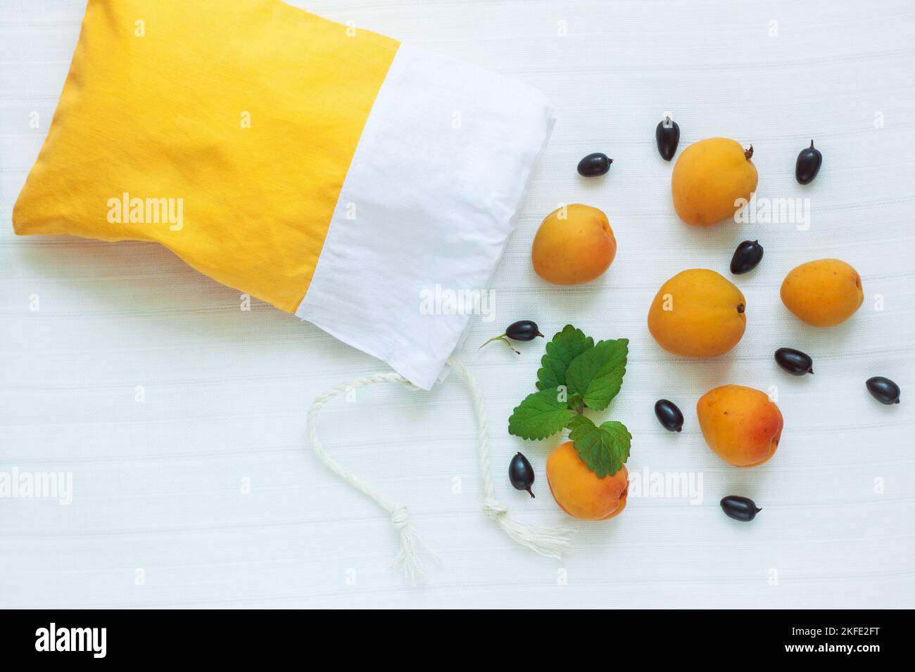 Sac à provisions en coton avec abricots, courants noirs et feuilles de menthe sur fond blanc. Respect de l'environnement, faible concept de plastique, zéro déchet, mindfu Banque D'Images