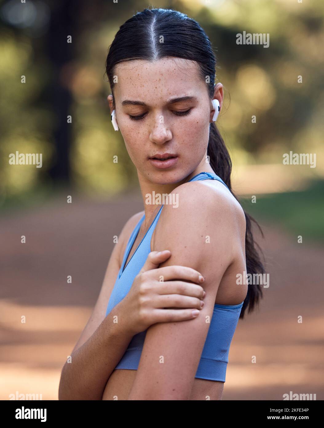 Femme, écouteurs et fitness douleur d'épaule dans l'environnement de la nature séance d'entraînement, développement durable de bois d'entraînement ou exercice de forêt. Coureur, athlète sportif et Banque D'Images