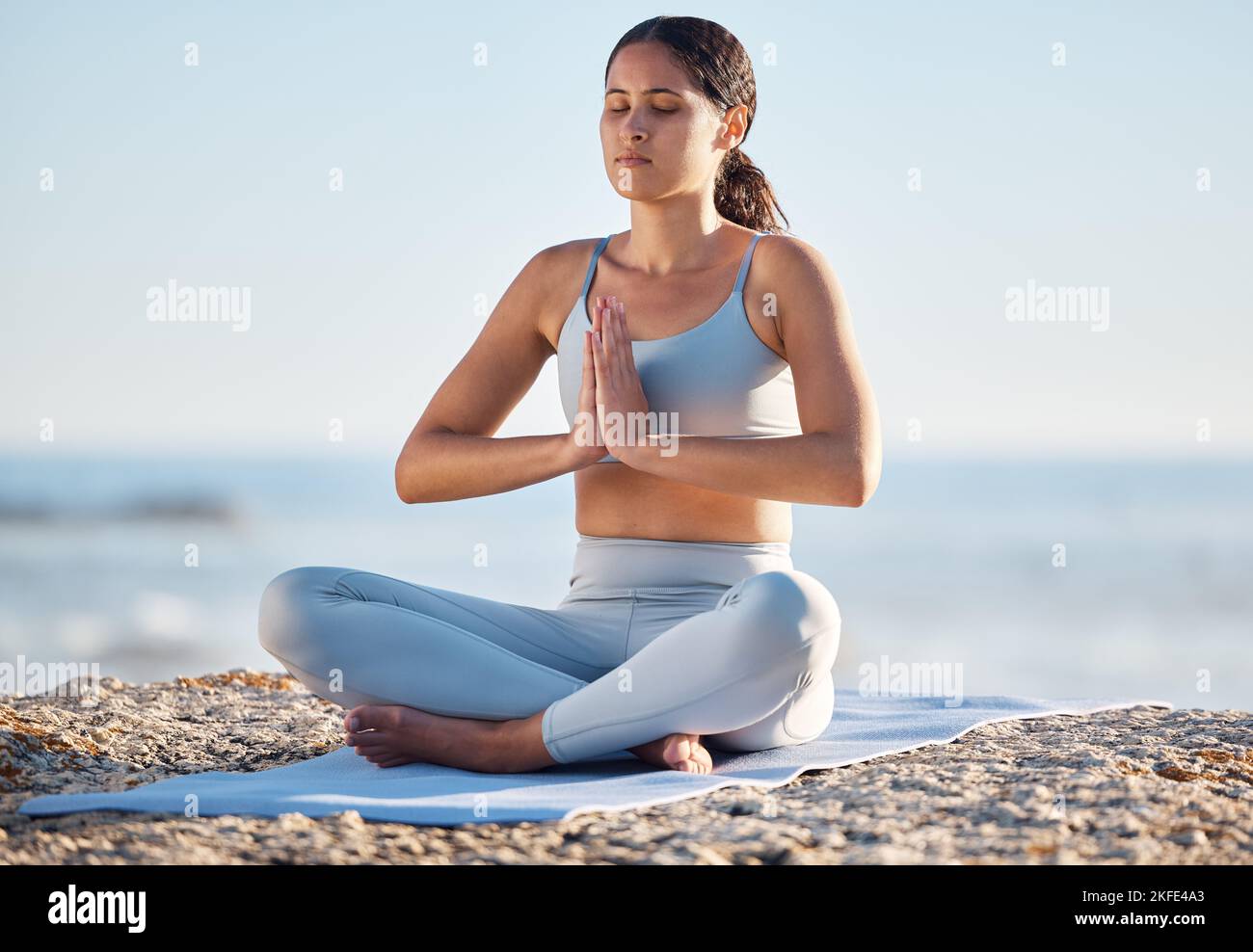 Femme, yoga et plage pour la forme physique, la santé et le bien-être avec un exercice de pleine conscience dans un environnement de nature. Mer, pilates et de la forme femelle dans lotus poser sur Banque D'Images