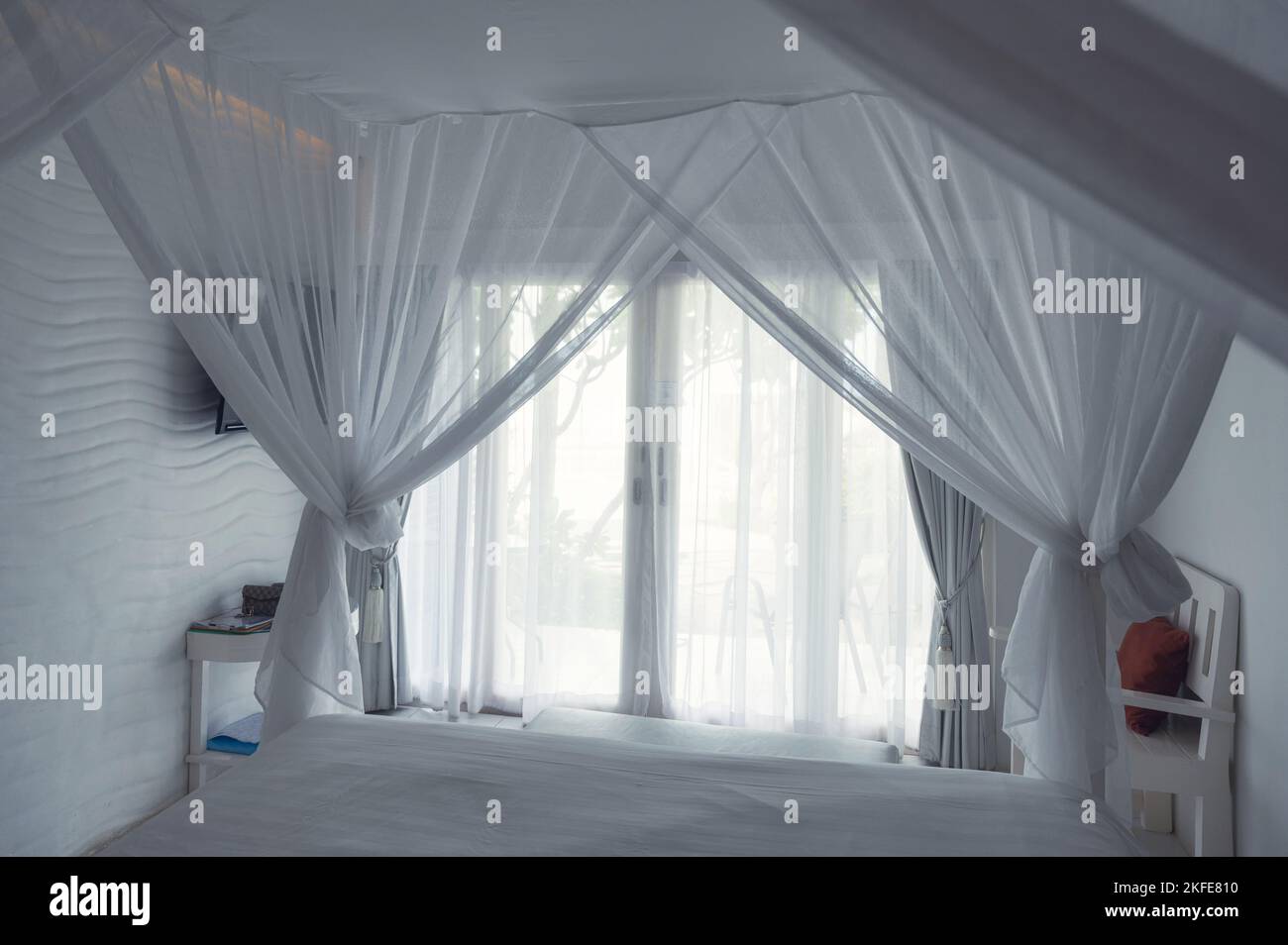 Intérieur de la chambre blanche avec moustiquaire et rideau, lumière du soleil qui brille à travers la porte, vacances et concept de vacances Banque D'Images