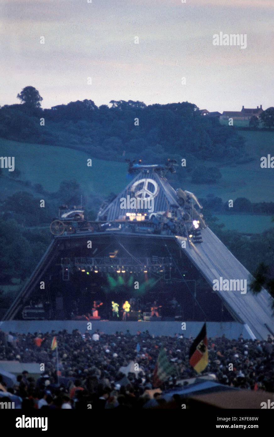 Les lundis heureux jouent à la Pyramide Stage à Glastonbury, samedi 23 juin 1990. Vous pouvez juste faire la danse distinctive de Bez dans son haut bleu. Les champs vides derrière la scène ont été achetés par Eavis au début de 90s et maintenant le festival remplit toute la vallée. Cette incarnation de l'étape Pyramide a brûlé en 1994. Photo © ROB WATKINS Banque D'Images