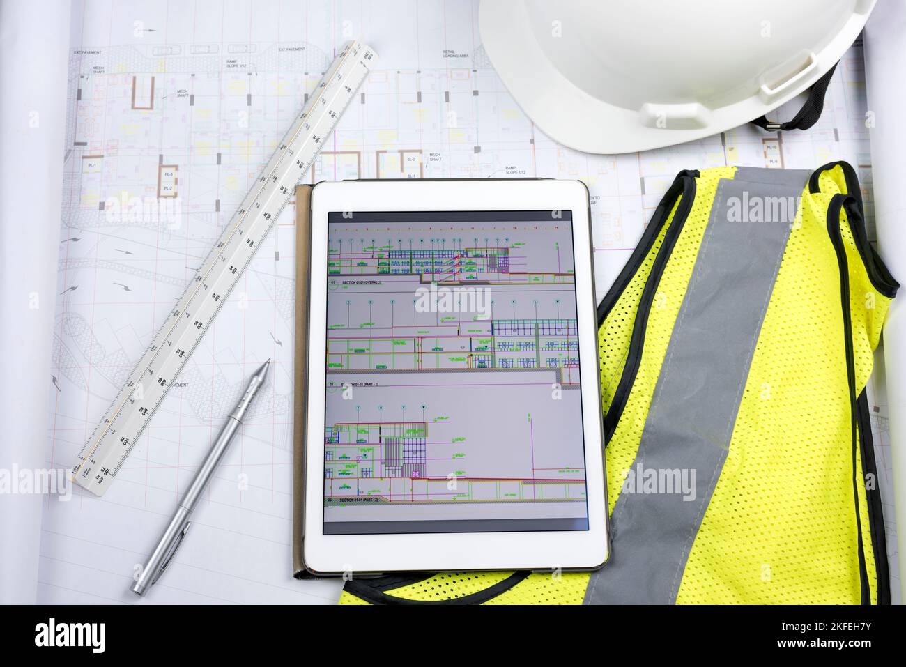 Tablette numérique avec dessin, copie papier du dessin, règle triangulaire et équipement de protection individuelle, gilet jaune de sécurité Banque D'Images