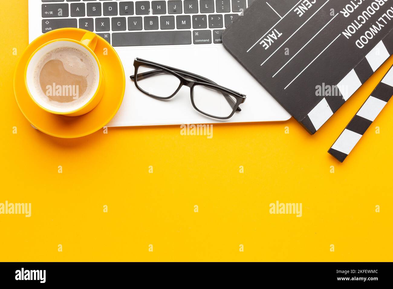 Bureau avec film clapper, ordinateur portable, tasse à café, sur table jaune - vue de dessus prise de vue. Photo de haute qualité Banque D'Images