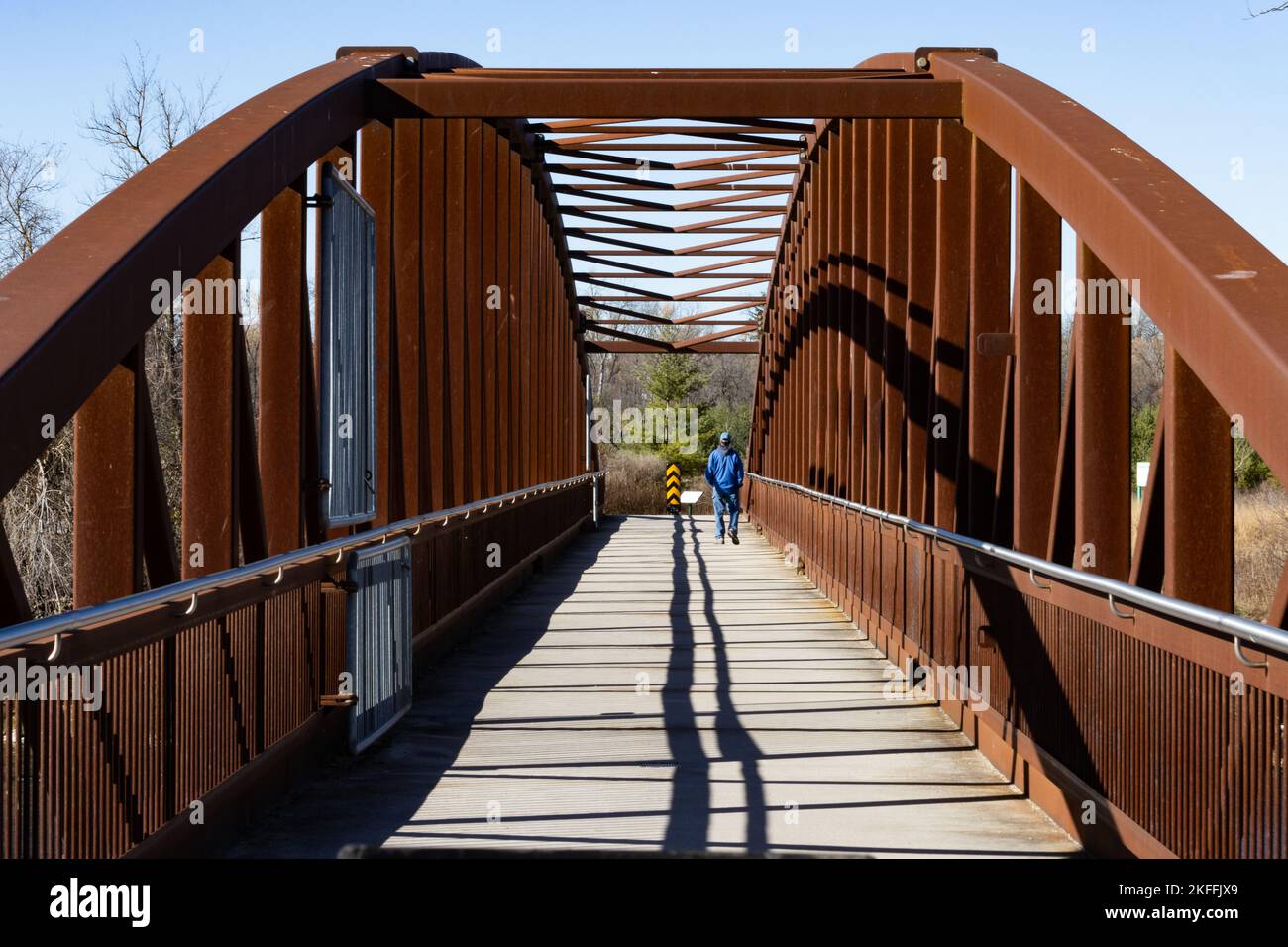 Un homme se déplace sur un pont piétonnier en acier rouge au-dessus de la rivière Grand Banque D'Images