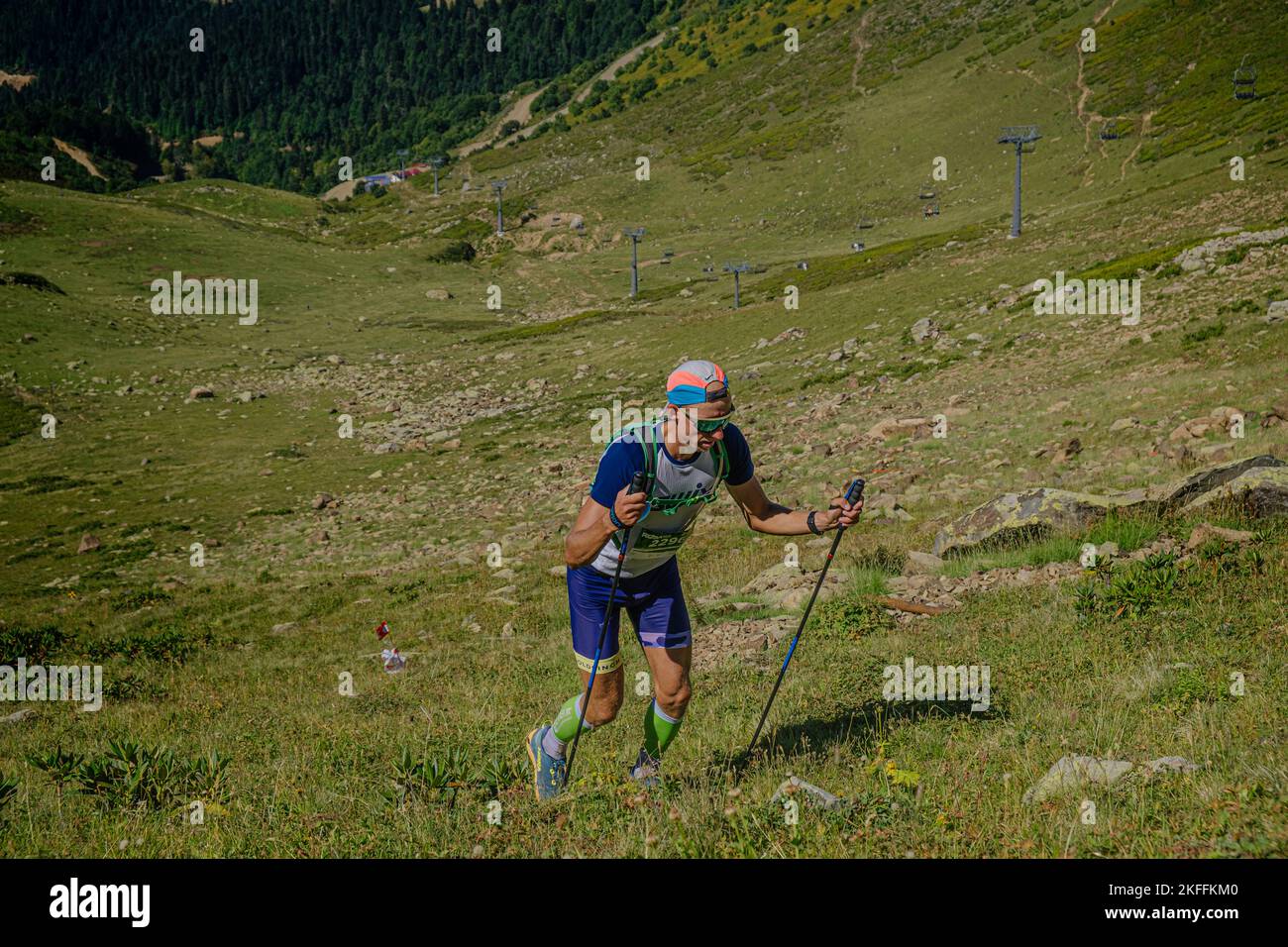 Rosa Khutor, Russie - 10 septembre 2022: Athlète masculin avec des bâtons de randonnée grimpant en amont dans le sentier sauvage de Rosa Banque D'Images Rosa Khutor, Russie - 10 septembre 2022: Athlète masculin avec des bâtons de randonnée grimpant en amont dans le sentier sauvage de Rosa Banque D'Images