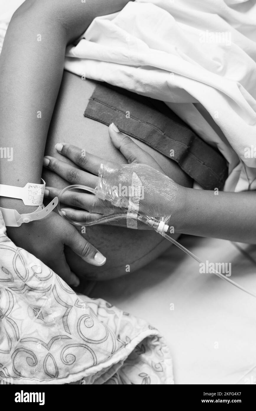 Femme enceinte au travail, couchée dans un lit d'hôpital attendant la naissance de son bébé. Banque D'Images