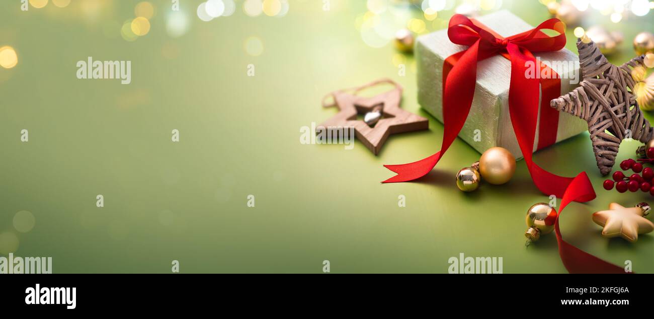 Carte de vœux de Noël ou bannière de Noël - boîte cadeau et ornements sur fond vert clair avec lumières magiques Banque D'Images