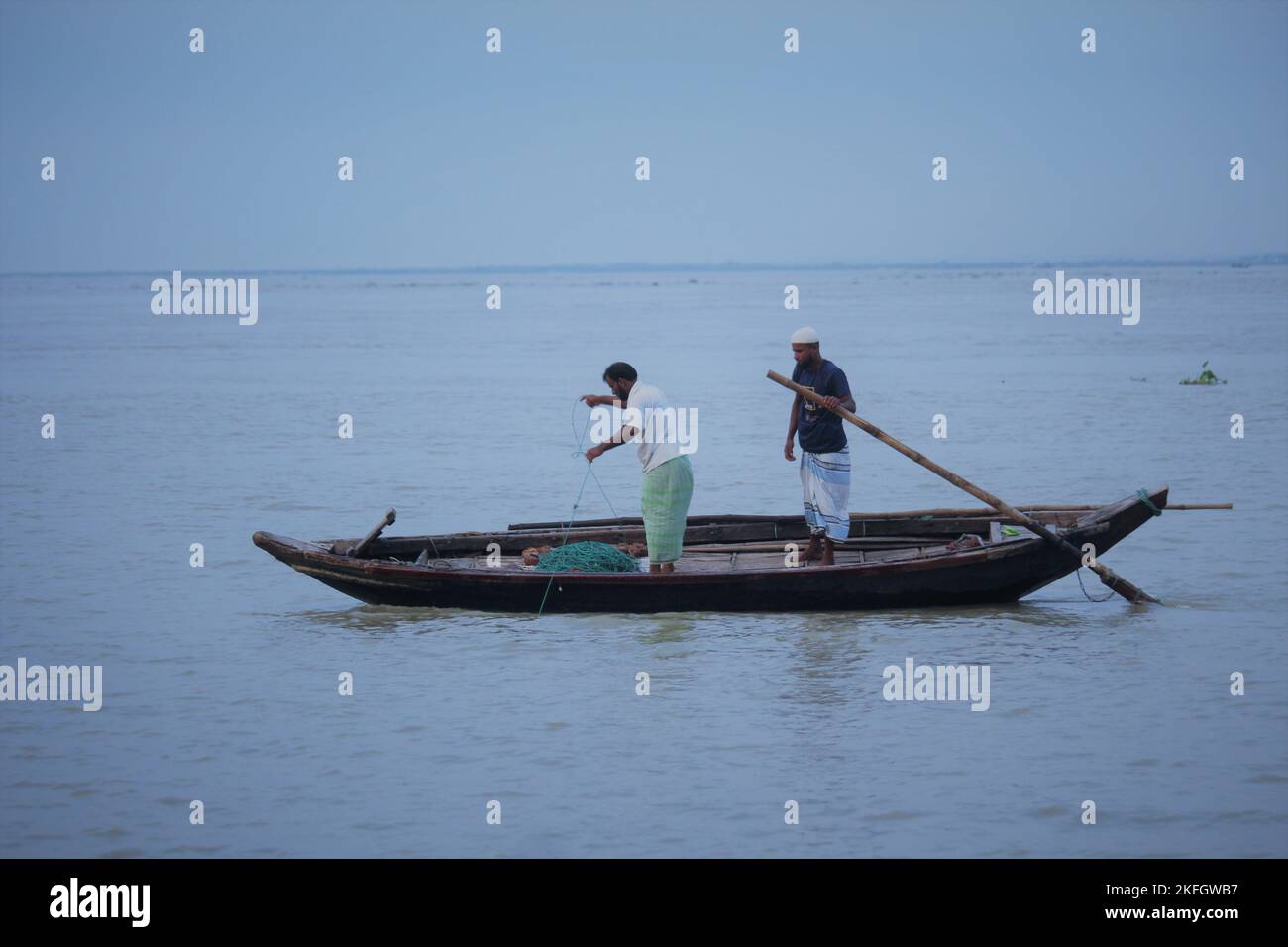 Deux personnes pêchent de la hilsa dans la rivière en bateau. Banque D'Images