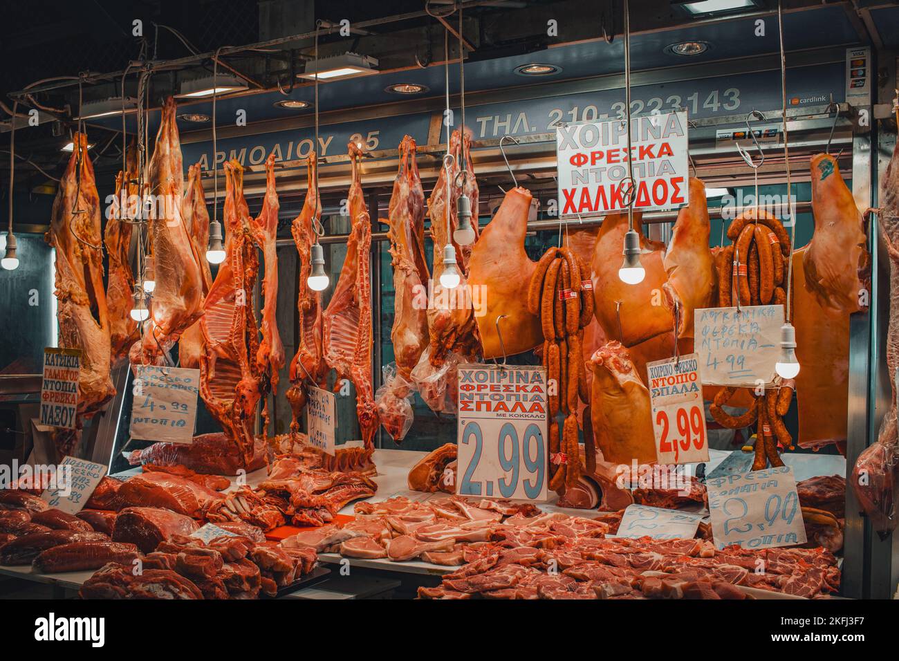 Stand de vendeur local avec plusieurs sortes de réunions suspendues dans le marché municipal central d'Athènes avec étiquettes de prix jointes. Banque D'Images