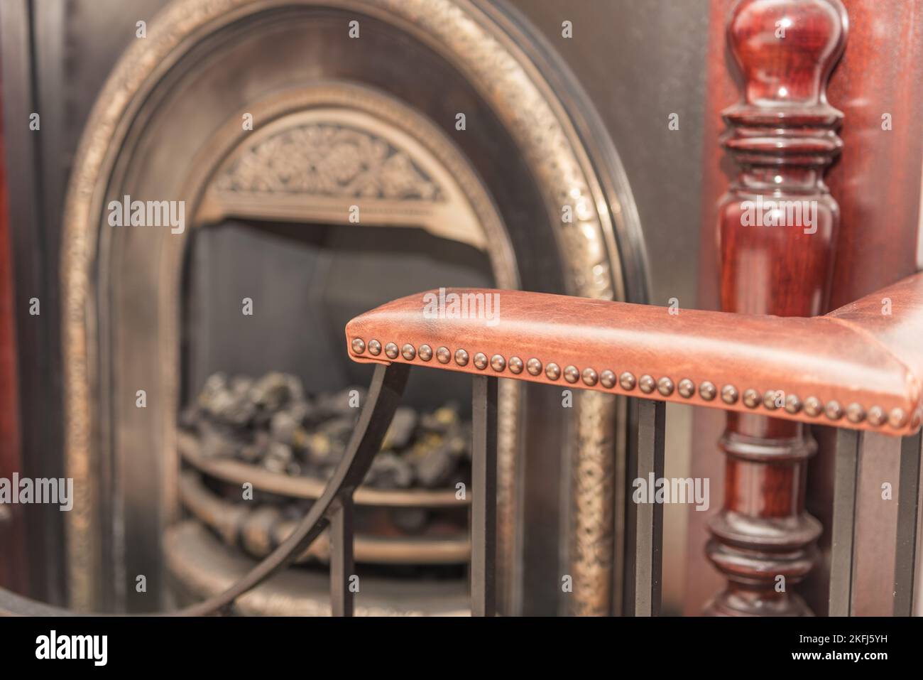 Sièges d'angle anciens en cuir et cadre de feu avec clous en laiton. Feu de fer et de laiton lieu et pièce de manteau flou dans l'arrière-plan. Luxe int Banque D'Images