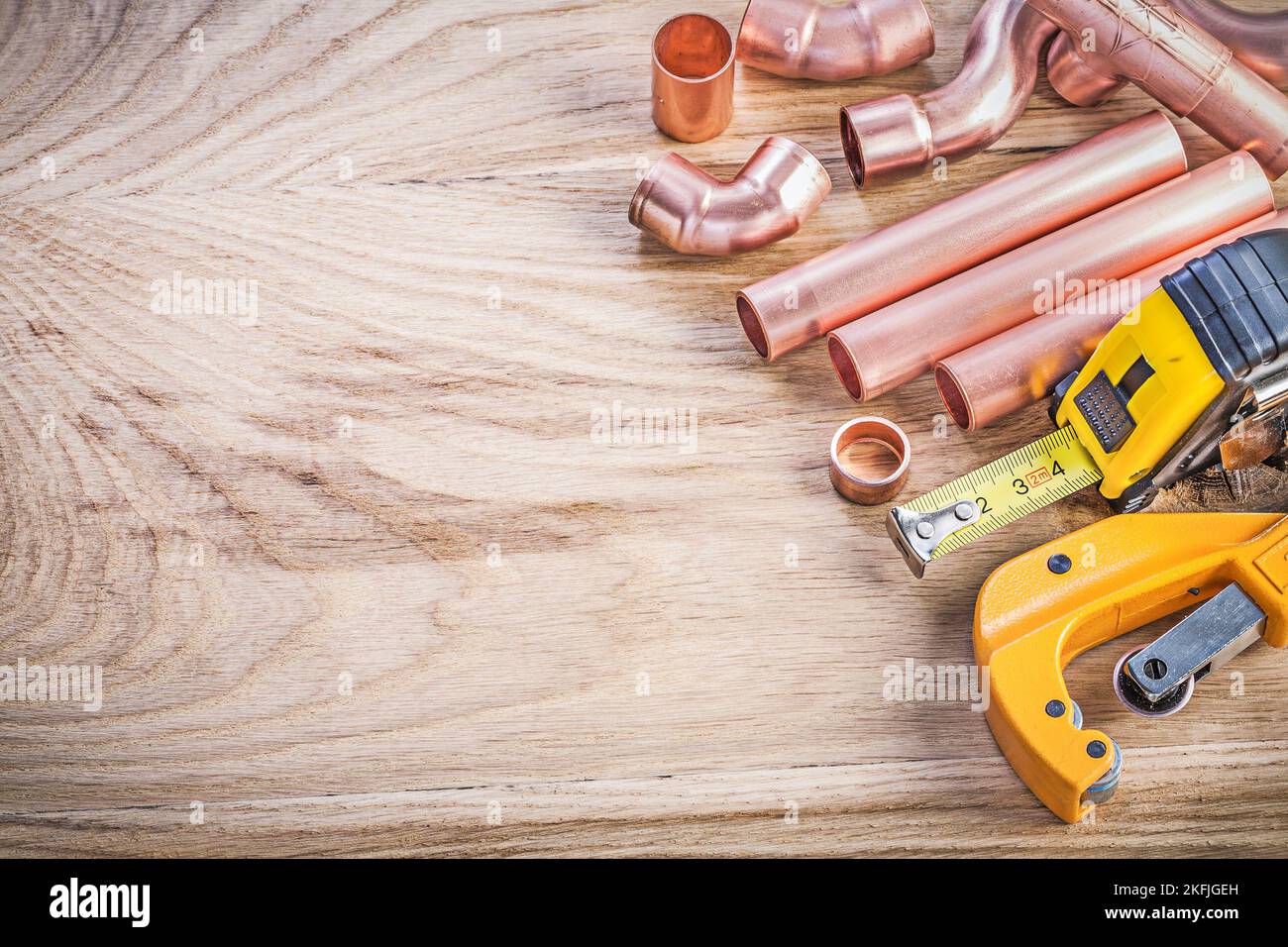 Jeu de raccords de coupe-tuyaux en cuivre ruban adhésif sur le concept de la verrerie de plomberie en bois. Banque D'Images