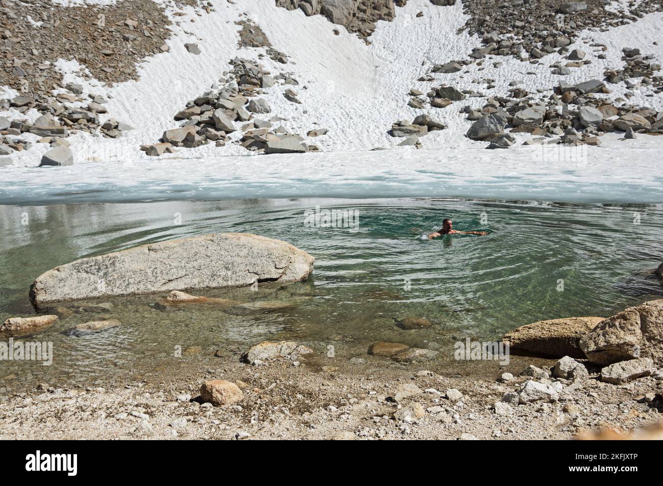 homme nageant dans un lac de montagne froide avec de la neige Banque D'Images