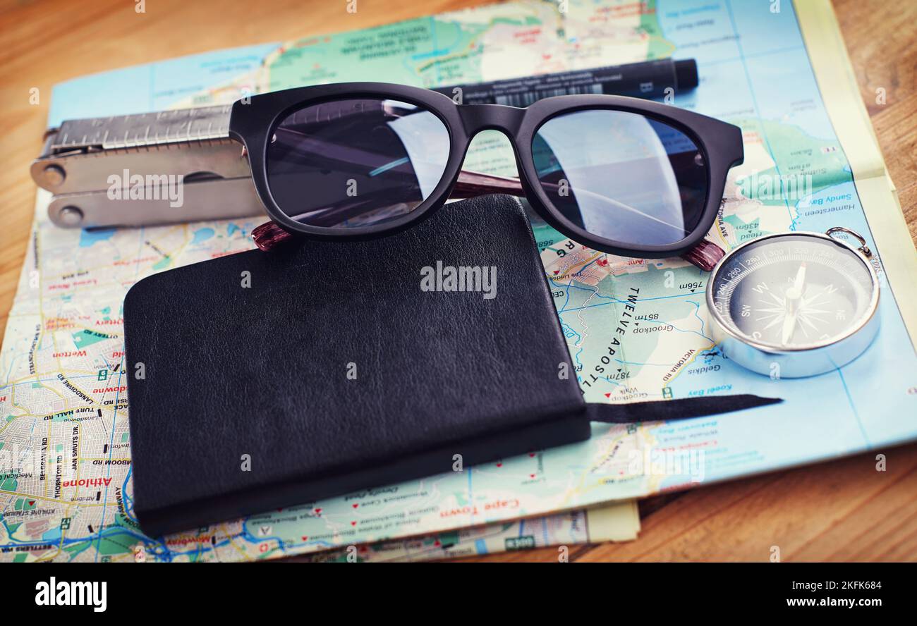 Prêt à voyager. Gros plan de lunettes de soleil, un carnet, une boussole et un outil utilitaire sur une carte. Banque D'Images