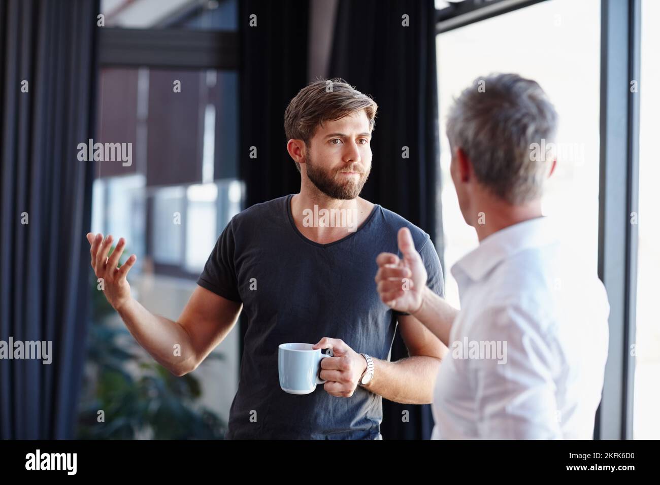 Se baisser à une conversation sérieuse. Deux hommes d'affaires beaux ayant une discussion dans le bureau. Banque D'Images