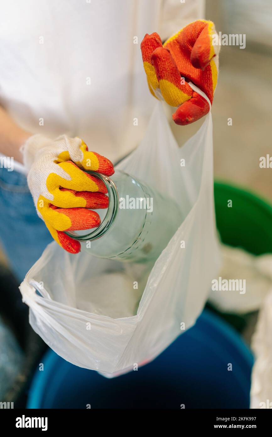 Plan vertical de travail de femme volontaire non reconnaissable mains dans des gants triant des bouteilles de verre à l'usine privée de recyclage des déchets pour plus loin Banque D'Images