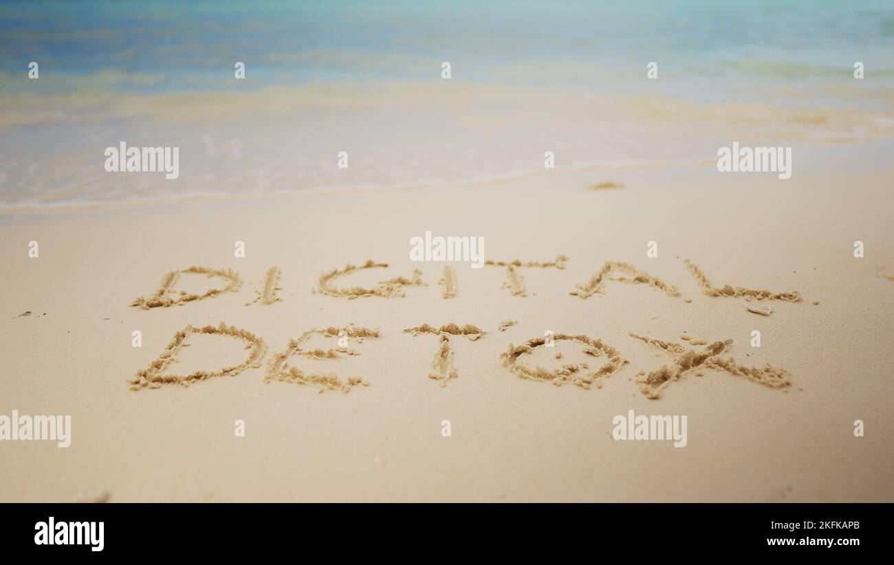 Detox numérique mot écrit sur le sable près de la mer à la plage Banque D'Images