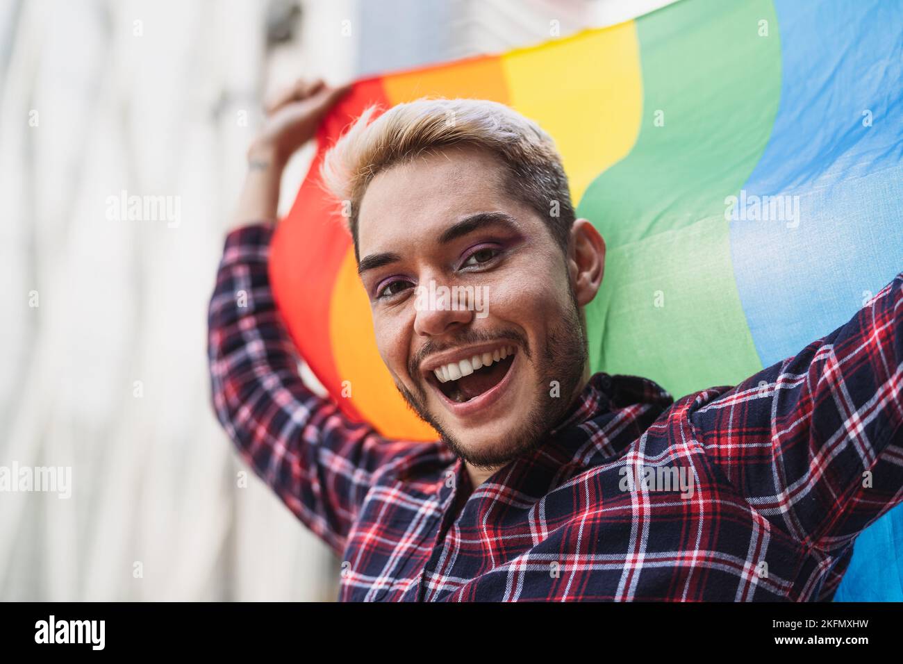 Un homme gay heureux célébrant le festival de la fierté avec le drapeau arc-en-ciel LGBTQ Banque D'Images