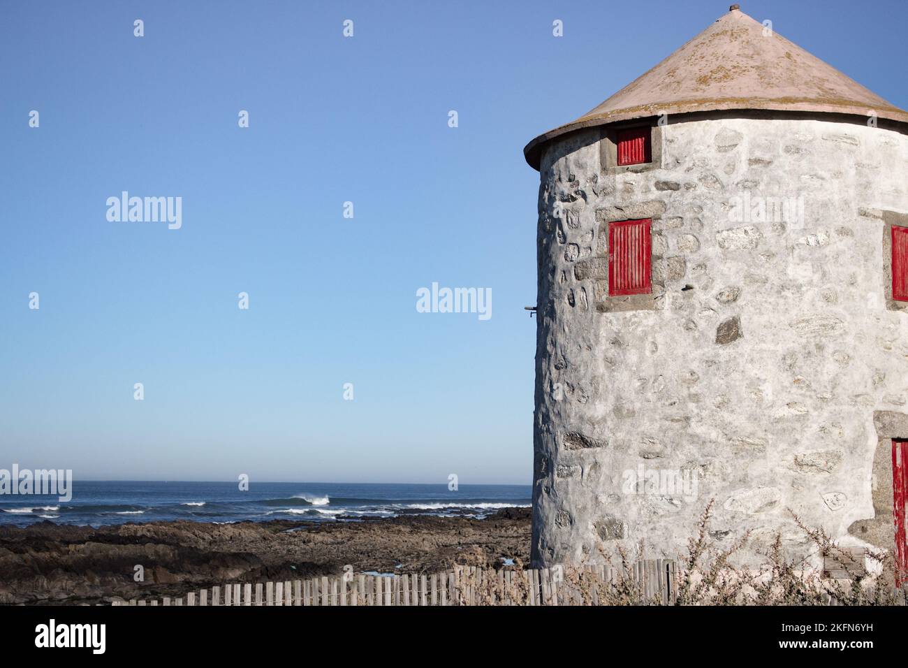 Ancien phare abandonné avec porte rouge fermée et fenêtres sur la côte atlantique de l'océan, Portugal. Phare contre ciel bleu avec espace de copie. Banque D'Images