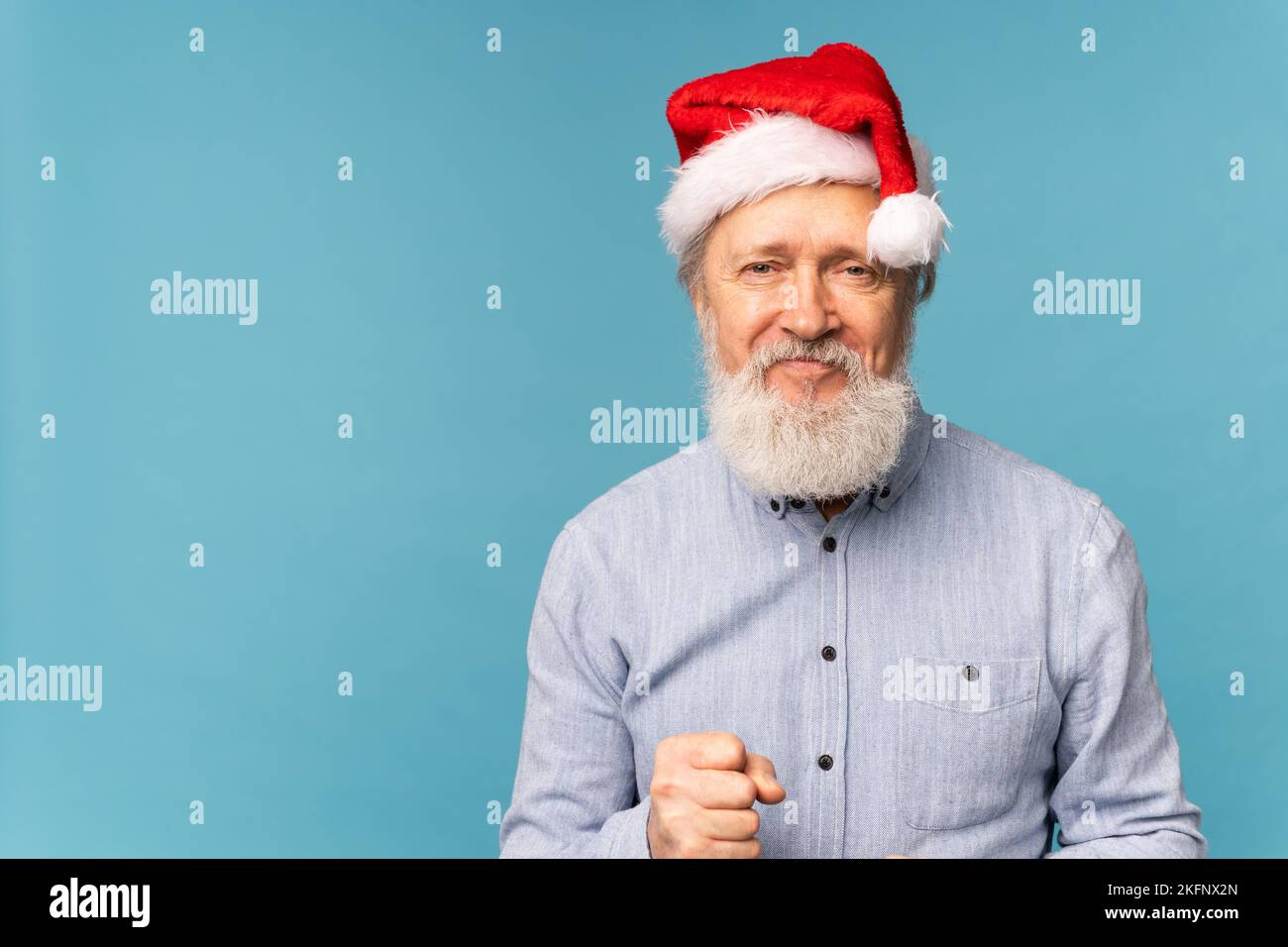 Heureux confiant et cool Old barbu Santa Claus gagnant raing poing célébrant le triomphe et le succès sur fond bleu avec l'espace de copie Banque D'Images