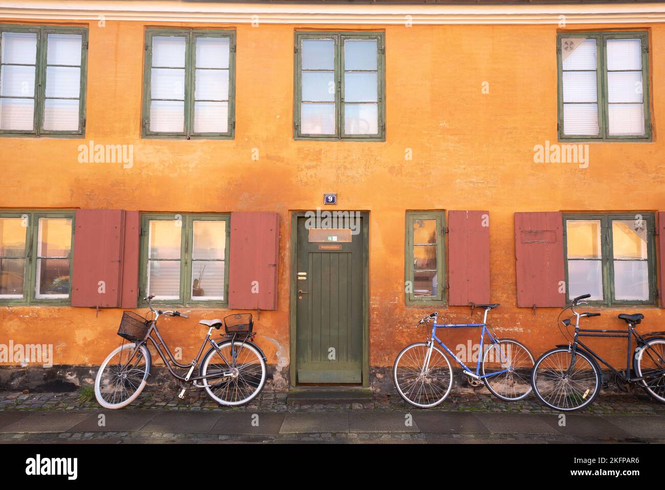 Bicyclettes à l'extérieur d'une maison à Nyboder, un quartier historique de maisons en rangée d'anciennes casernes navales à Copenhague, au Danemark. Maisons jaunes à Copenhague. Banque D'Images