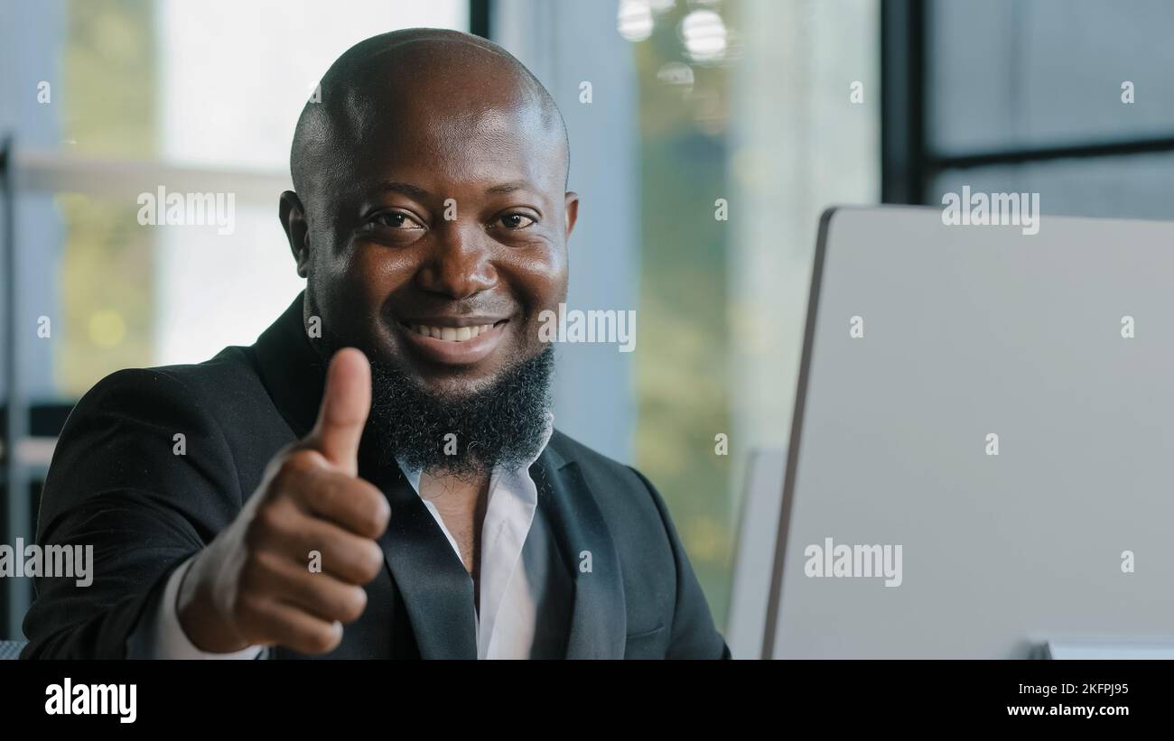 Homme d'affaires africain adulte heureux plus grand gars satisfait avec l'ordinateur de saisie d'application sur ordinateur portable dans le bureau souriant recommander bon choix bonne idée signe Banque D'Images