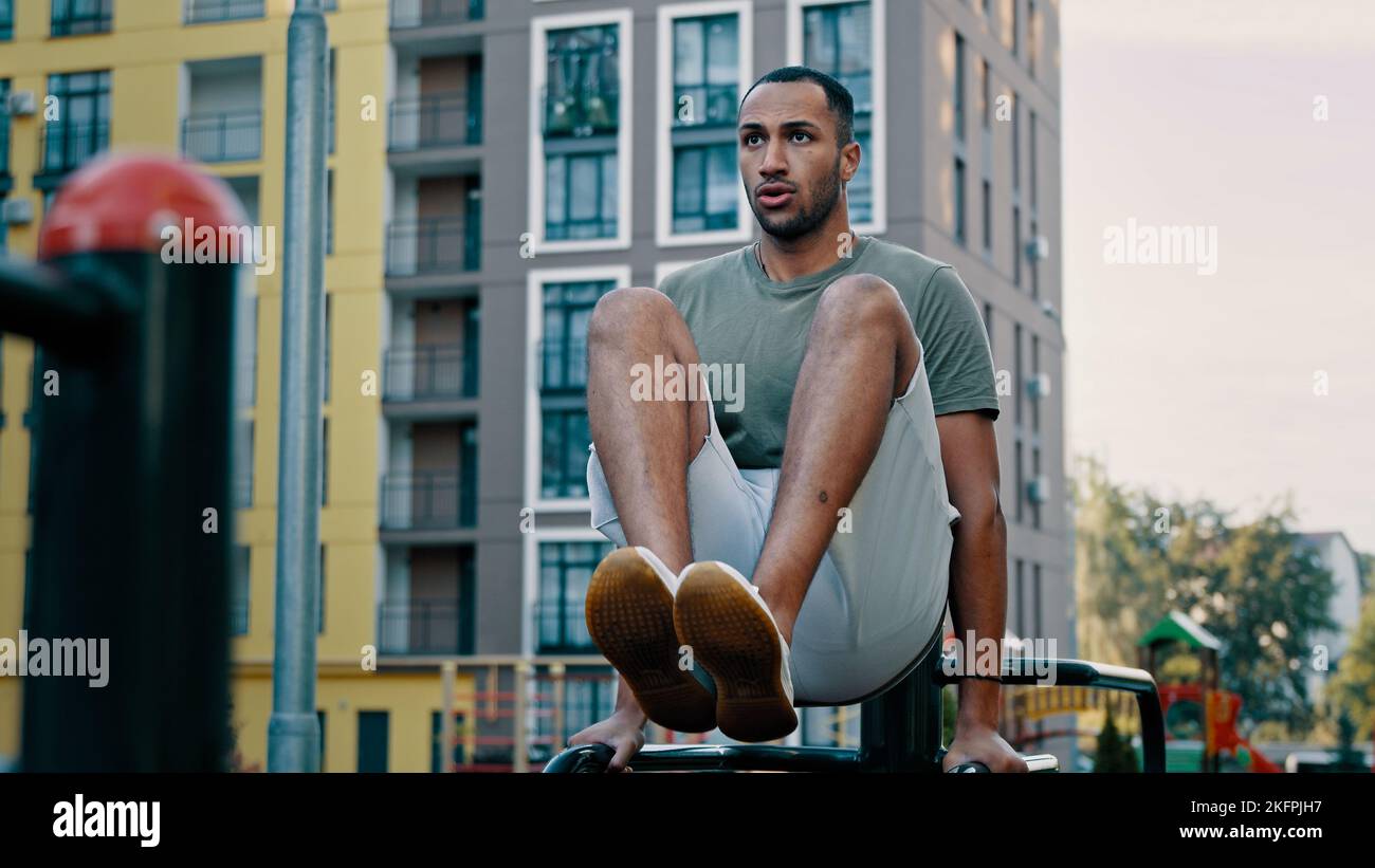 Puissant latina sportif gymnaste musclé africain américain sain homme levant les jambes sur les bars ville sport gym entraînement appuyer abs muscles. Athlète masculin Banque D'Images