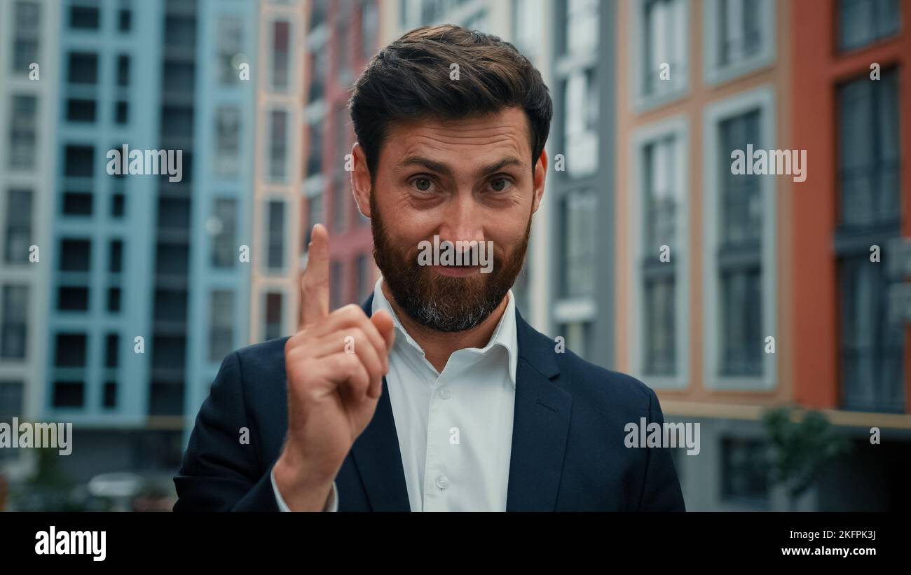 Adulte homme d'affaires caucasien homme d'affaires patron stand à l'extérieur dans la ville en serrant sterly index doigt regardant la caméra signe de l'attention d'accord avec le bien Banque D'Images