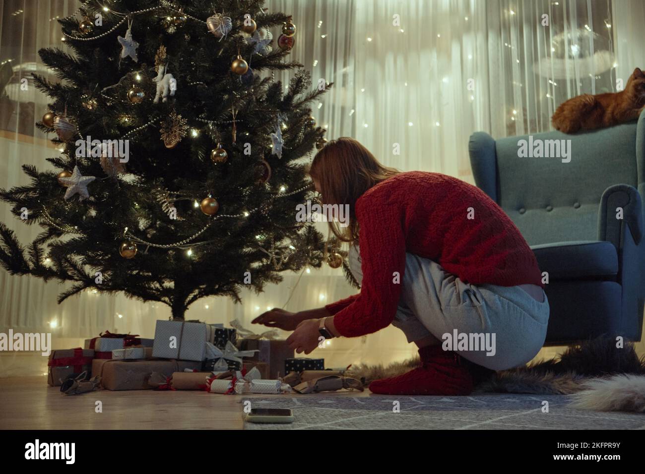 Femme mettant des cadeaux sous l'arbre de Noël la veille de Noël ou la veille du nouvel an la nuit Banque D'Images