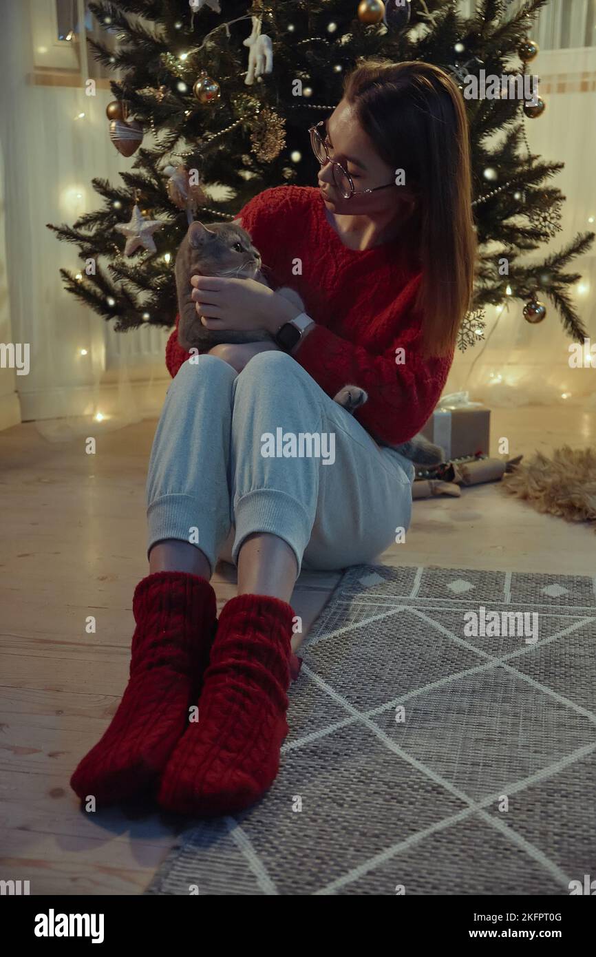 Jeune femme avec un chat assis près de l'arbre de Noël, Noël avec un chat d'animal de compagnie Banque D'Images