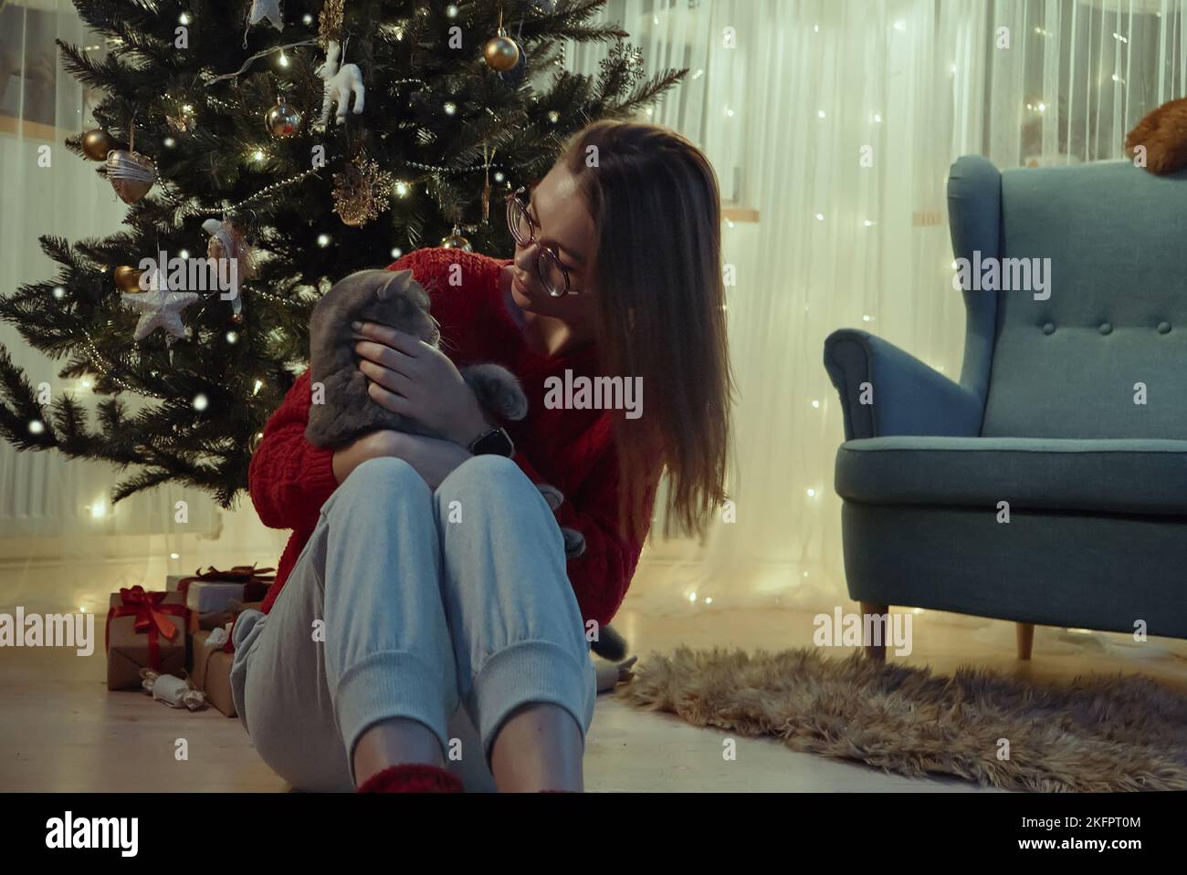 Jeune femme avec un chat assis près de l'arbre de Noël, Noël avec un chat d'animal de compagnie Banque D'Images