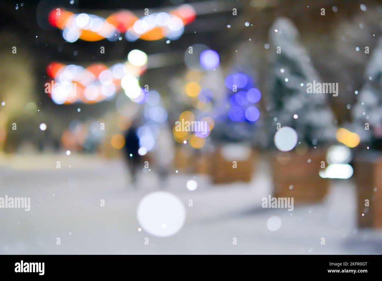 Résumé arrière-plan flou. Beaucoup d'arbres de Noël décorés se tiennent le long de la rue décorée avec un éclairage lumineux, des lumières lumineuses et des guirlandes dans la ville pendant de fortes chutes de neige la nuit d'hiver Banque D'Images