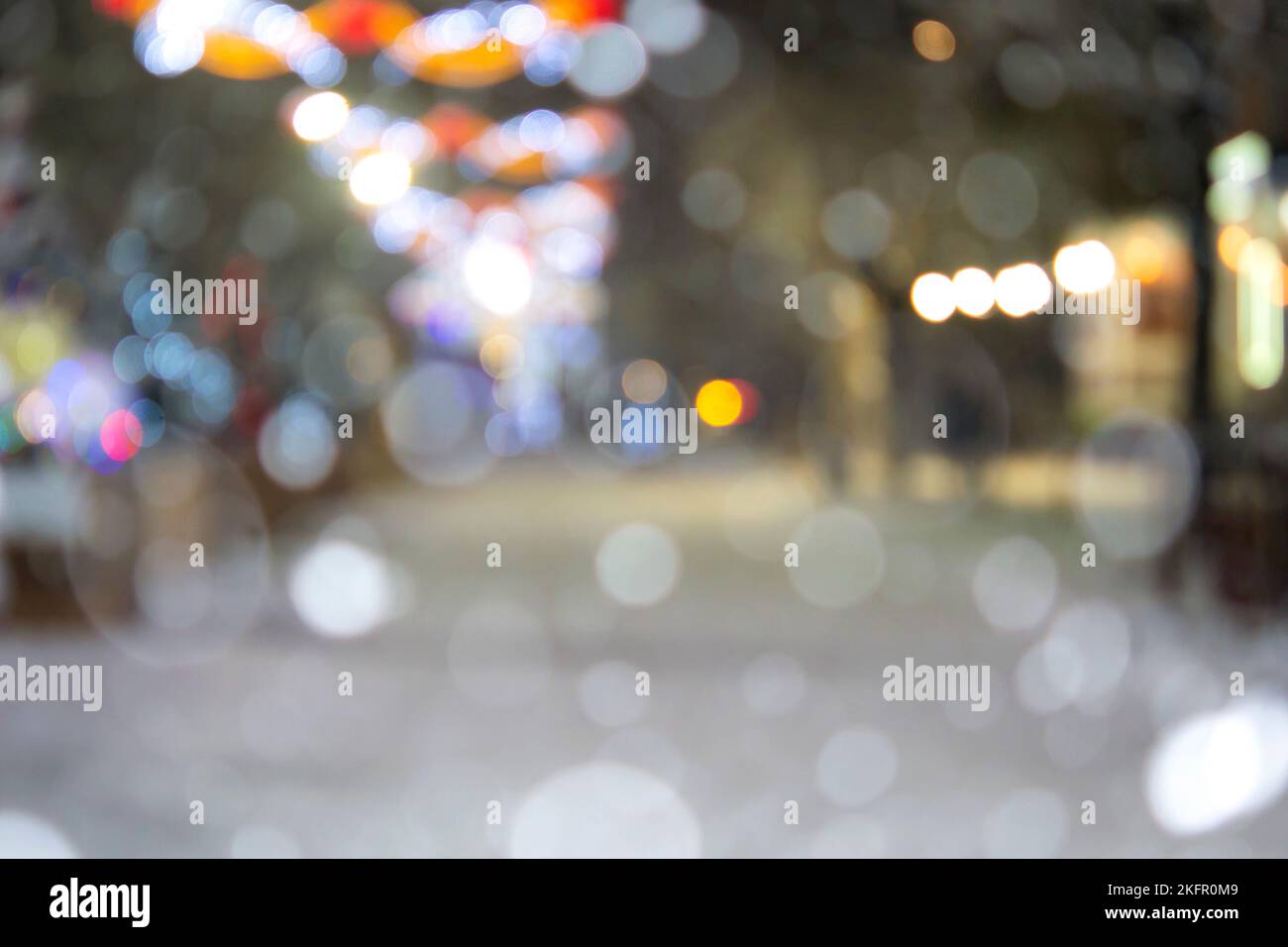 Résumé arrière-plan flou. Personnes marchant dans la rue d'arbres de Noël décorés décorés avec éclairage lumineux, lumières lumineuses et guirlandes dans la ville pendant de fortes chutes de neige la nuit d'hiver Banque D'Images