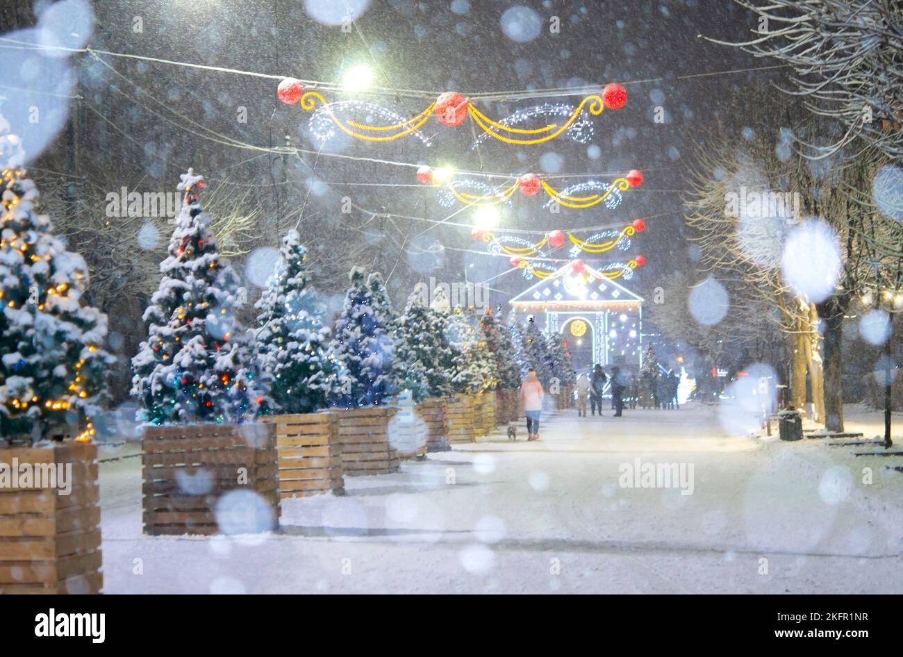 Rue de la ville pendant les chutes de neige en hiver. Beaucoup d'arbres de Noël décorés, éclairage, décoration sur la rue. Fête de Noël du nouvel an. Lanternes sur les arbres Banque D'Images