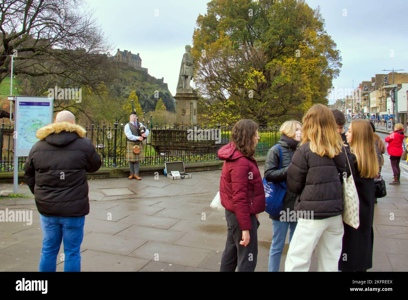 Les touristes écoutent un joueur de cornemuse sur la rue des princes Édimbourg sous la vue du château Banque D'Images